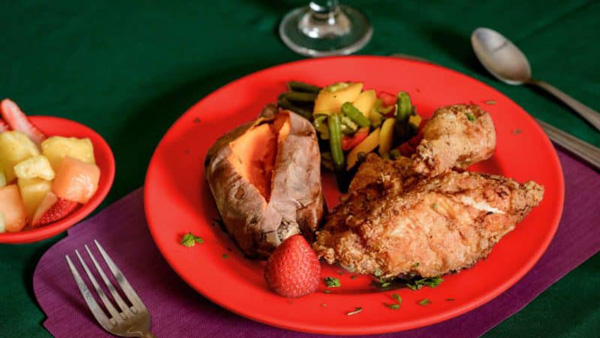 Fried chicken dinner with baked sweet potatoe, mixed vegetables and mixed fruit bowl