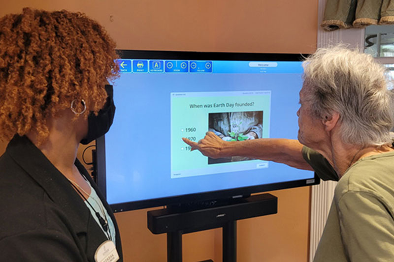 Staff member helping resident with memory improvement game at Superior Residences of Brandon