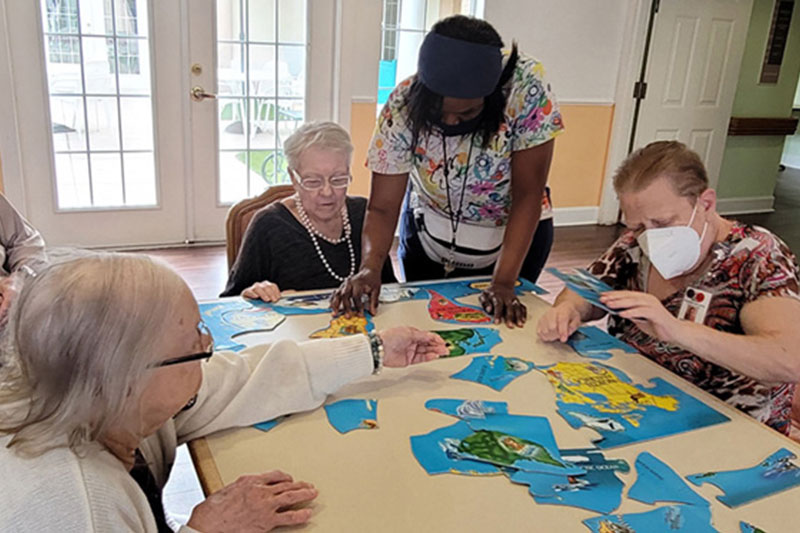 Staff member helping residents put a puzzle together at Superior Residences of Brandon