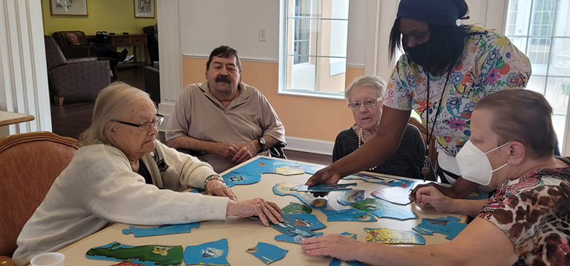 Staff member assisting residents as they put a puzzle together
