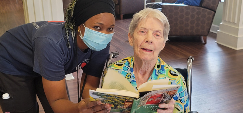 Staff member assisting resident while reading at Superior Residences of Brandon